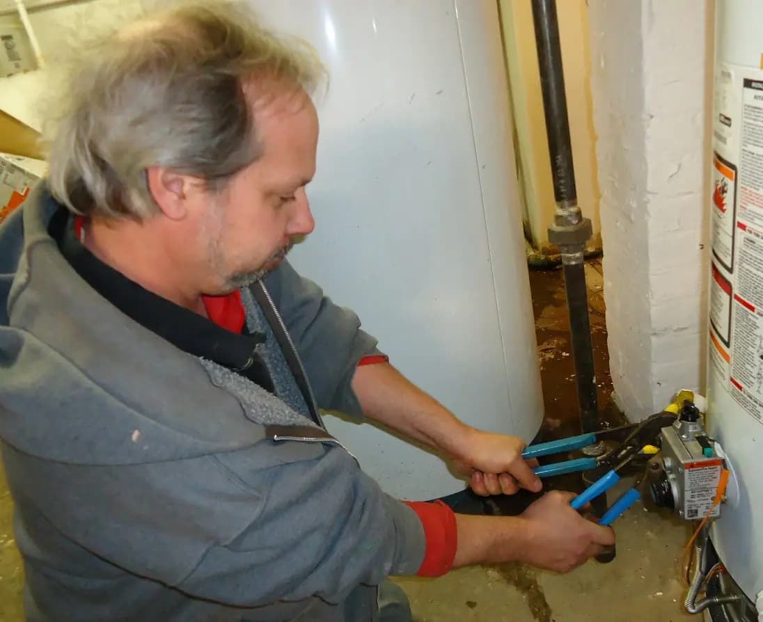 A plumber using two wrenches to work on a pipe fitting